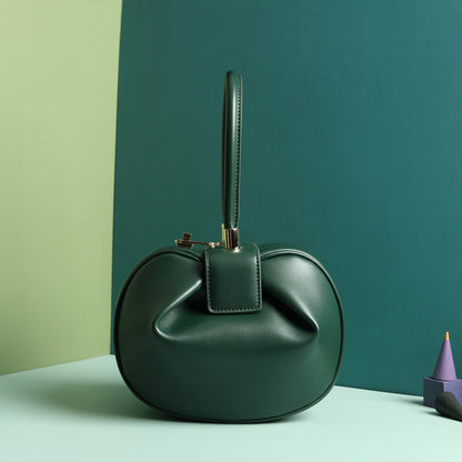 A green leather dumpling handbag with a buckle closure and a single handle, displayed against a two-tone background 