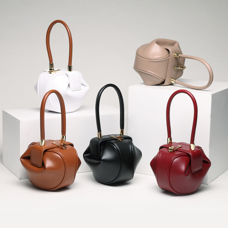 variety of leather dumpling handbag with a buckle closure and a single handle, displayed against a two-tone background 