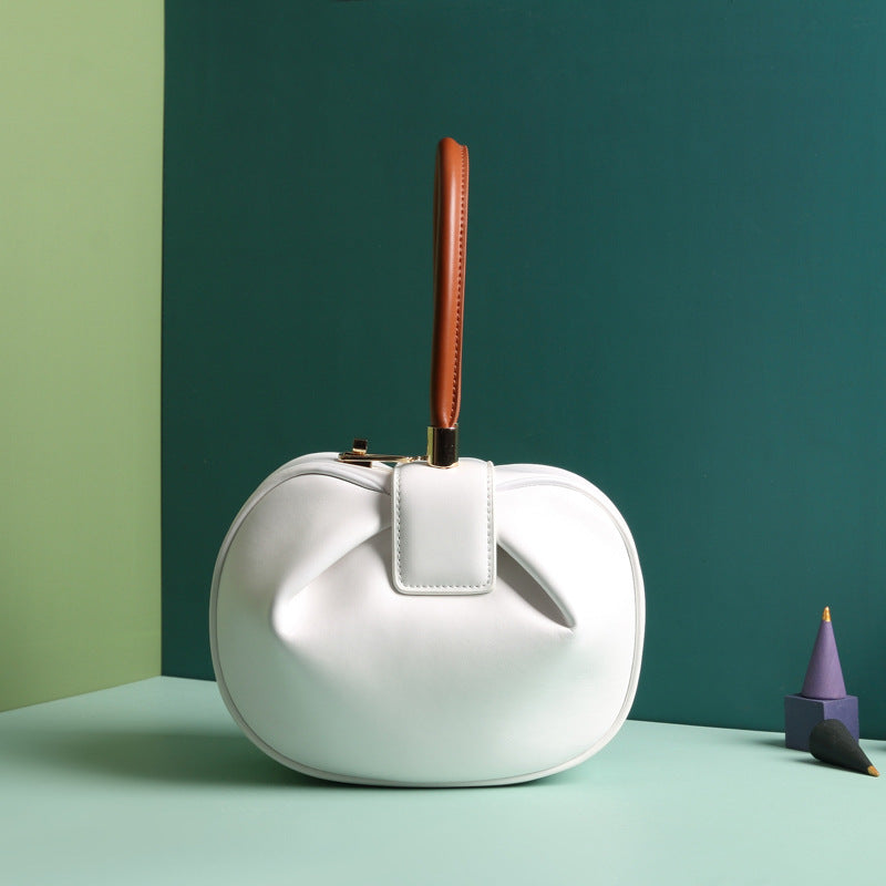 A white leather dumpling handbag with a buckle closure and a single handle, displayed against a two-tone background 