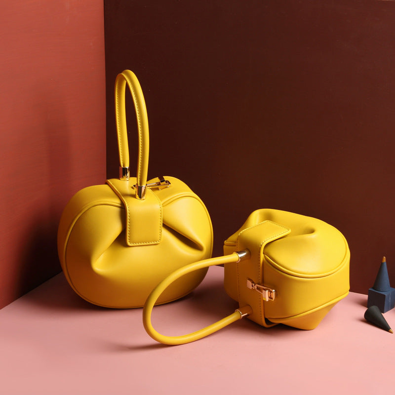 two yellow leather dumpling handbag with a buckle closure and a single handle, displayed against a two-tone background 