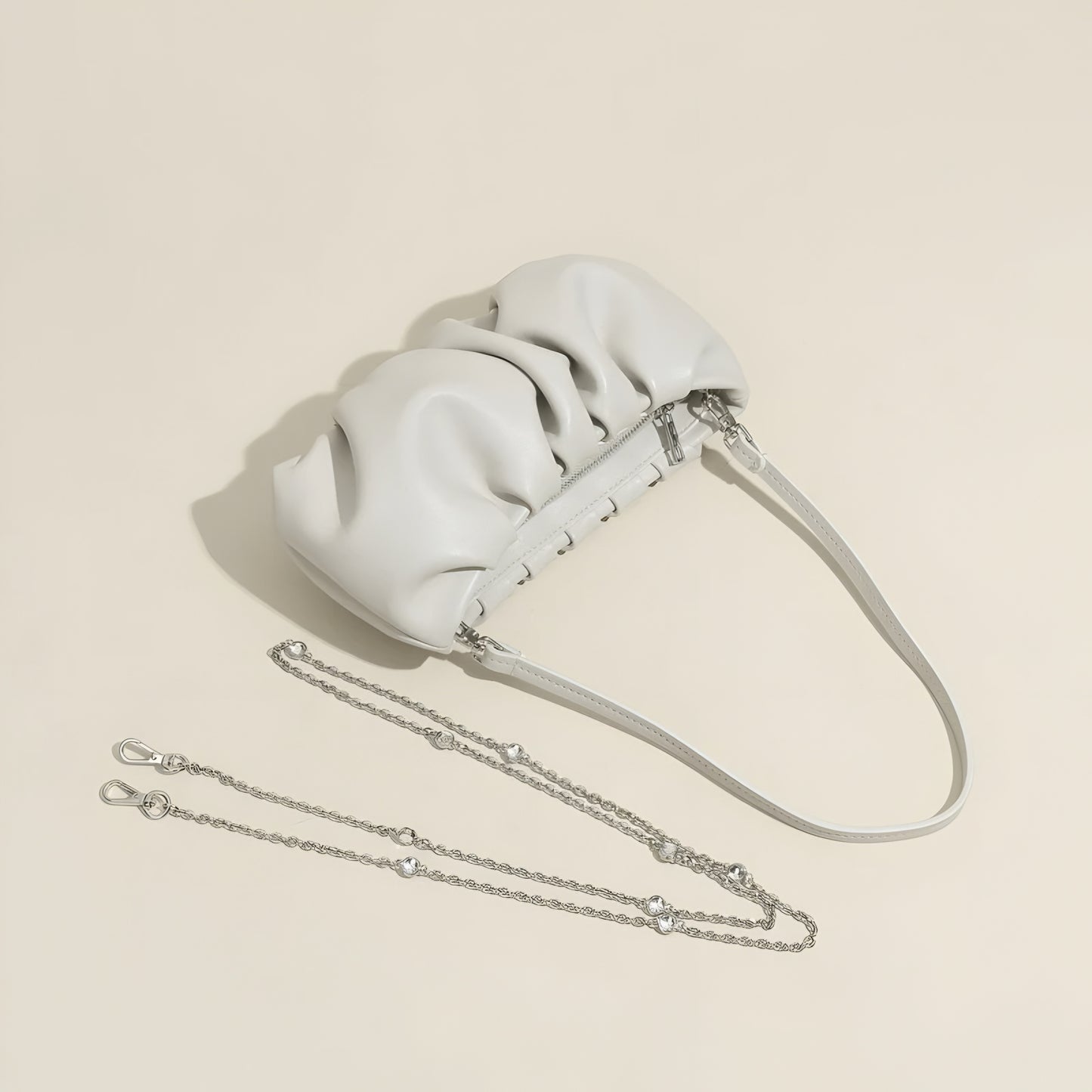 White real leather handbag with a  detachable chain strap and shoulder strap on a beige background
