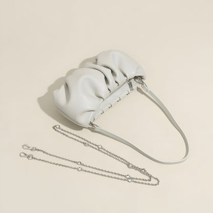 White real leather handbag with a  detachable chain strap and shoulder strap on a beige background