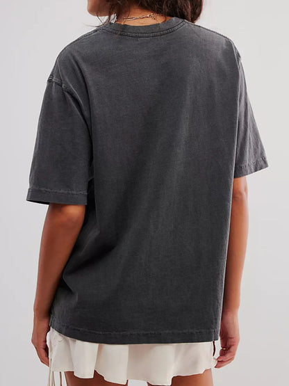 Back view of woman wearing a dark gray short sleeve loose t-shirt on a plain background