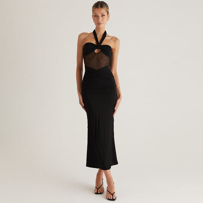 Woman wearing a black Halter Backless party maxi dress with sheer bodice detail on a plain background