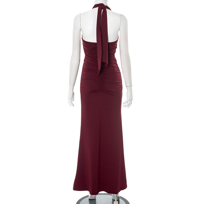 Back view of red/burgundy halter backless evening maxi dress on a mannequin against a white background
