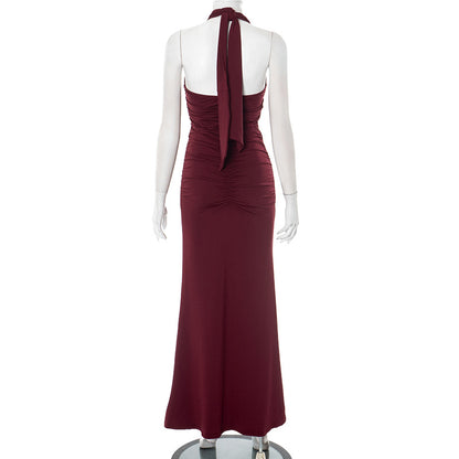 Back view of red/burgundy halter backless evening maxi dress on a mannequin against a white background