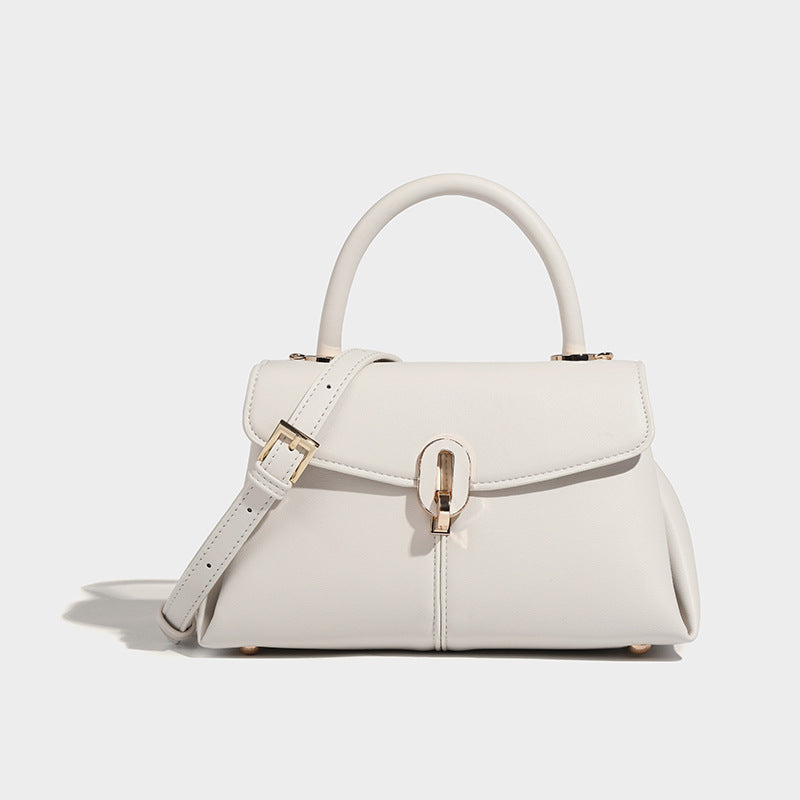 A white leather satchel handbag with a structured design, featuring a buckle closure, a hand handle, and a detachable strap.