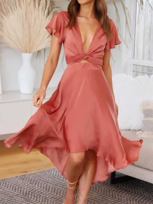 Model walking in coral high-low dress with flutter sleeves and deep v-neckline front view

