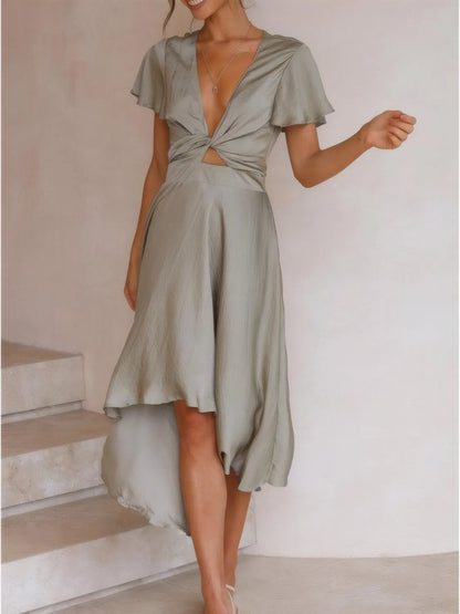 Model walking in sage high-low dress with flutter sleeves and deep v-neckline front view