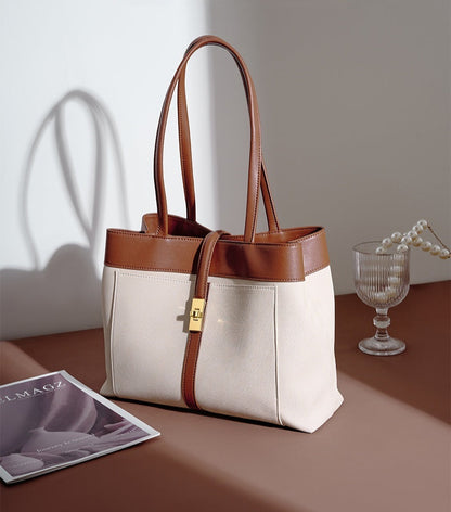 Brown and Beige genuine leather tote bag on a table with a glass of water and magazine.