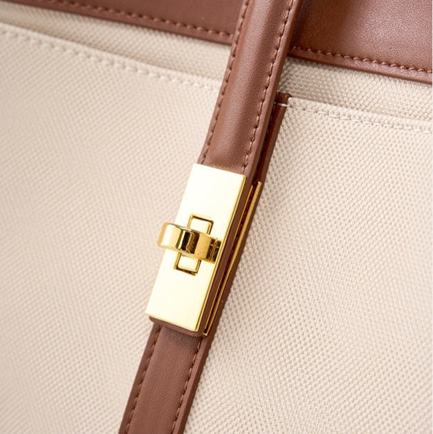 Close-up of a beige handbag with a brown  genuine leather strap and gold buckle on a white background.