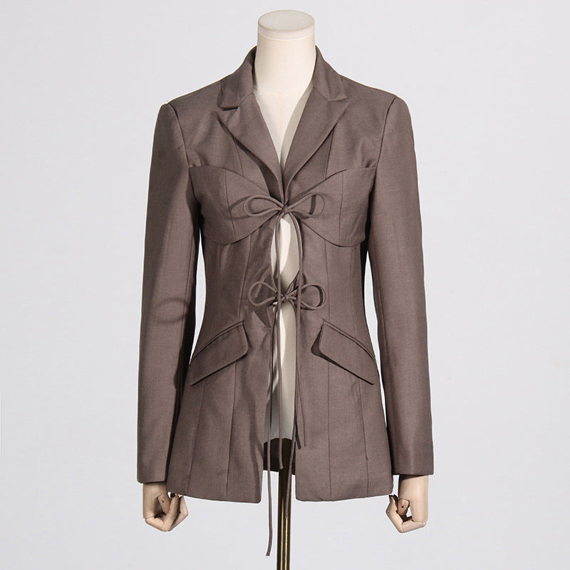 Front view of a luxury fashion inspired  beige/khaki hollow-out cinched irregular  longs sleeve blazer with a deep v-neckline and lace up front detail on a mannequin