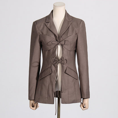 Front view of a luxury fashion inspired  beige/khaki hollow-out cinched irregular  longs sleeve blazer with a deep v-neckline and lace up front detail on a mannequin