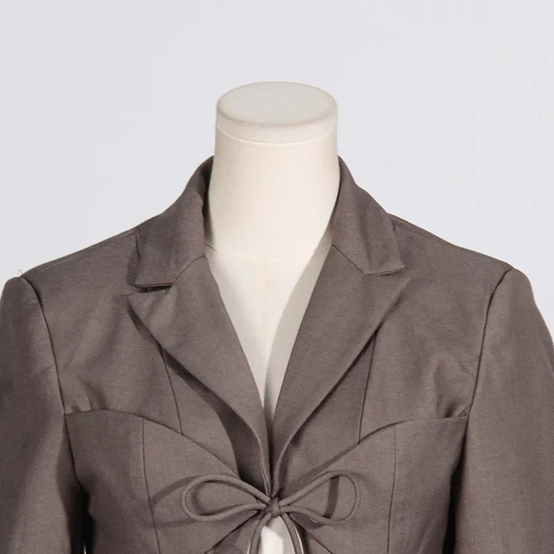 Close up of neckline of a luxury fashion inspired brown hollow-out cinched waist irregular long sleeve blazer on a mannequin