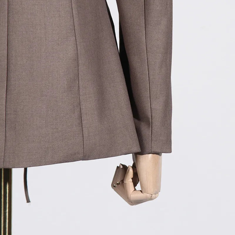 Close up of sleeve of a luxury fashion inspired brown hollow-out cinched irregular long sleeve blazer on a mannequin