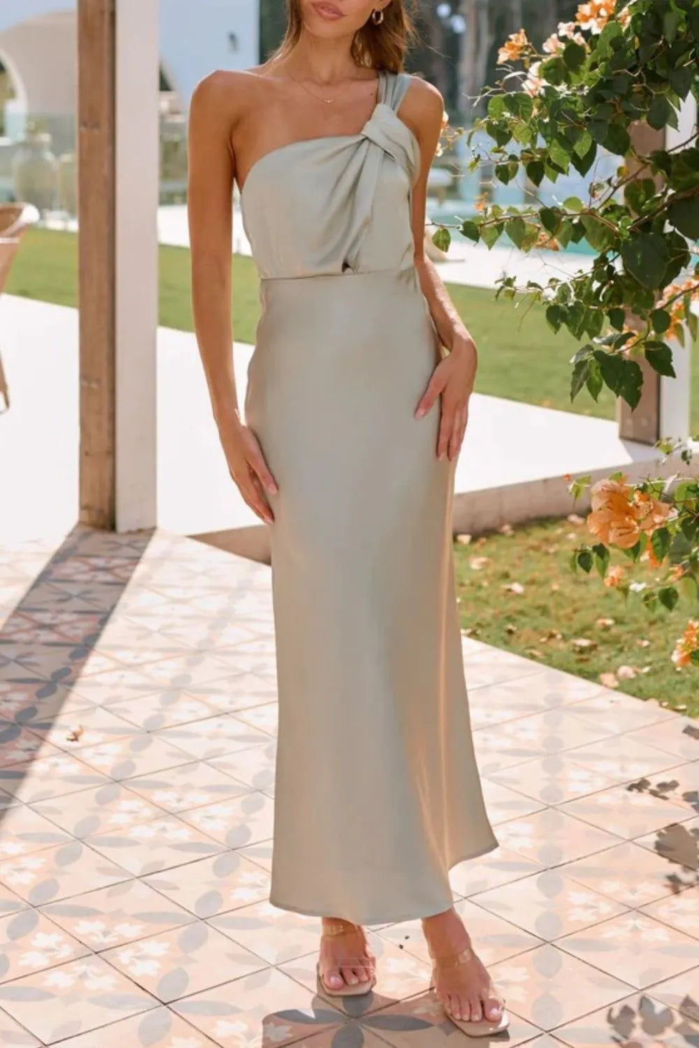 Model wearing asymmetrical  sage maxi dress showing knotted strap detail and flowy hem front view