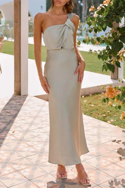 Model wearing asymmetrical  sage maxi dress showing knotted strap detail and flowy hem front view