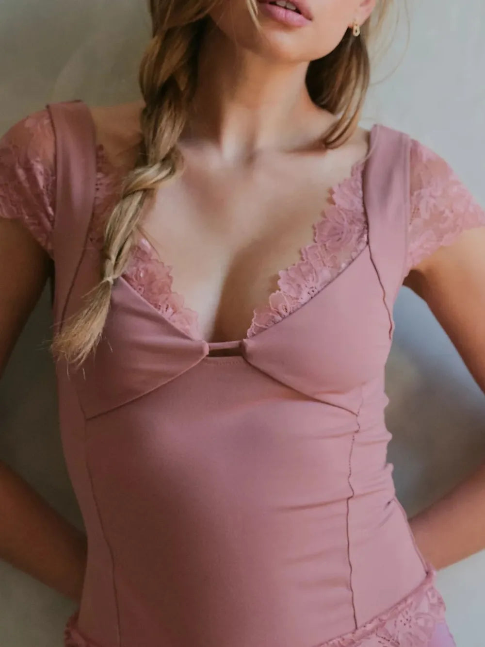 Woman wearing a pink Lace Detail V-Neck Cap Sleeve Top with a blurred background