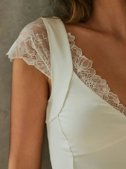 Close-up of a white/cream lace-trimmed v neck short sleeve top on a neutral background