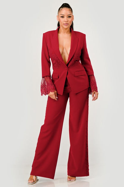 Woman wearing a red/burgundy wide-leg pants with matching blazer with lace details on a white background