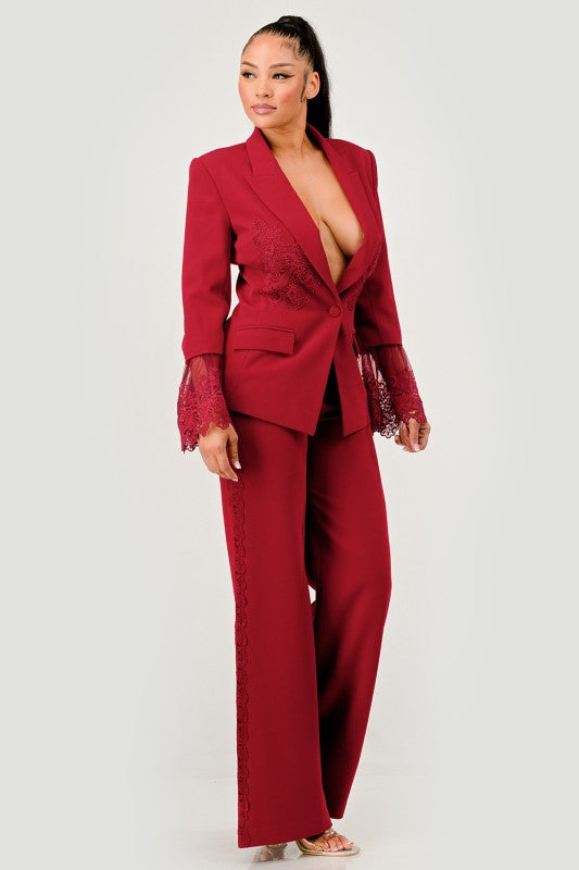 Model wearing a red/burgundy elegant women’s pantsuit with lace detailing with a white background