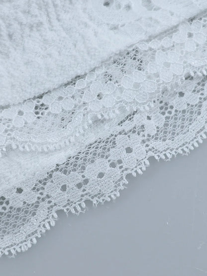 Close-up of white lace fabric hem of  Lace Off-Shoulder Maxi Dress with Flounce Sleeves on a light gray background