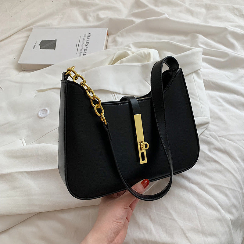 Black minimalist shoulder bag with gold chain strap detail

