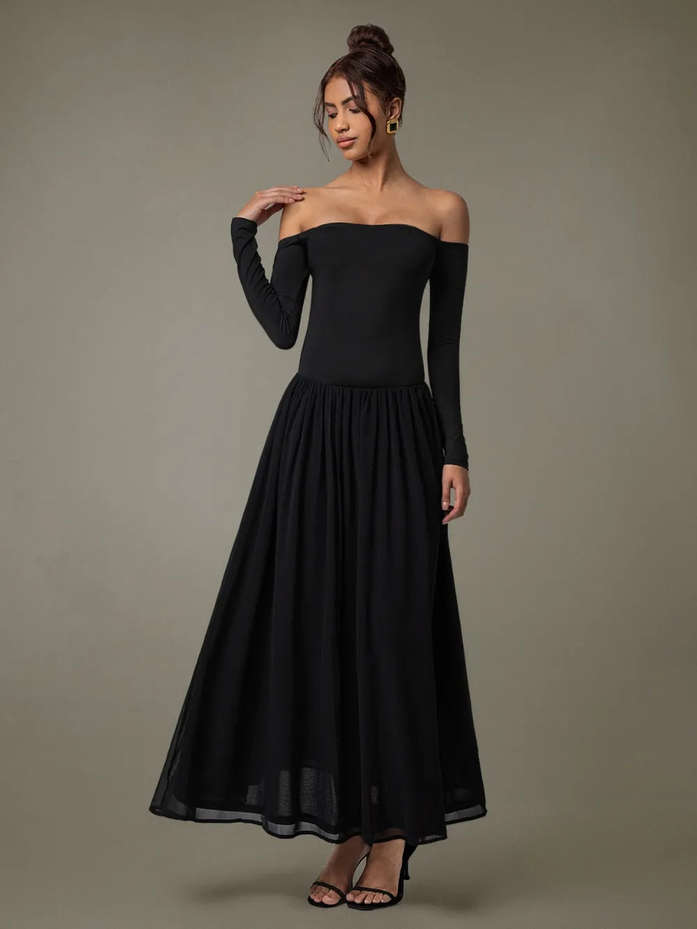 Model wearing off-shoulder long sleeve maxi dress in soft neutral tone background  with right hand on shoulder