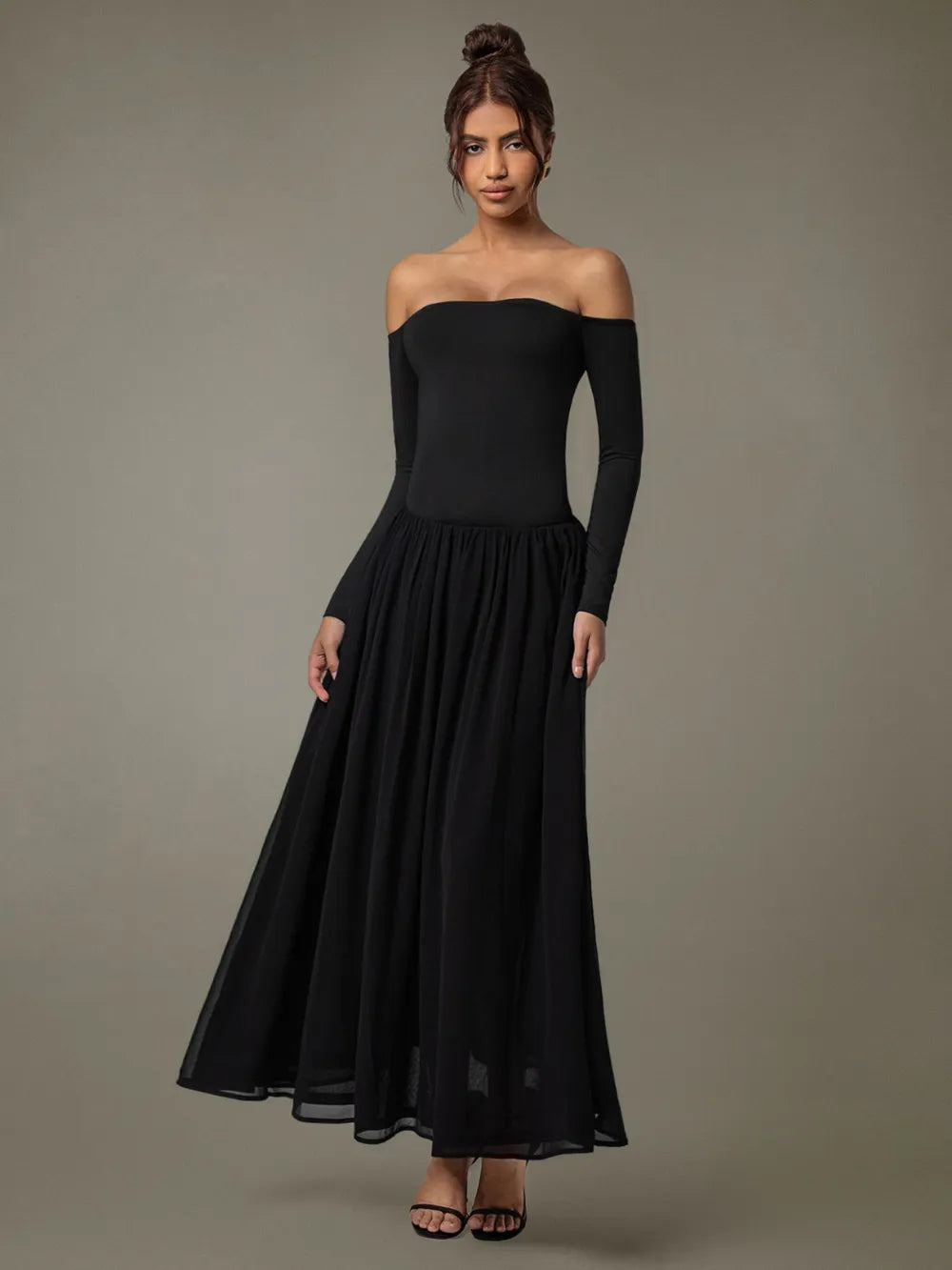 Model wearing off-shoulder long sleeve maxi dress front view in soft neutral tone background 