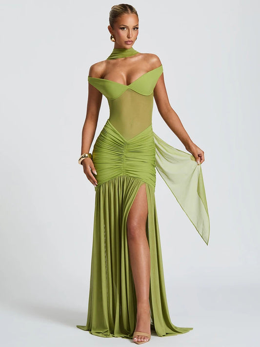 Woman in a green off shoulder backless high thigh slit maxi dress with flowy hem 
