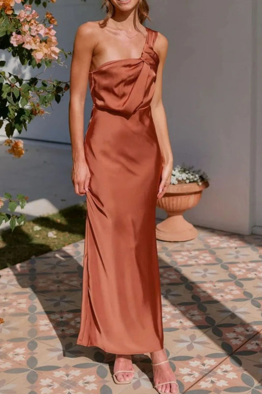 Woman wearing elegant one-shoulder dress on an outdoor floral setting