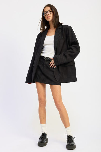 woman wearing a black oversized pinstripe blazer with button front on a white background