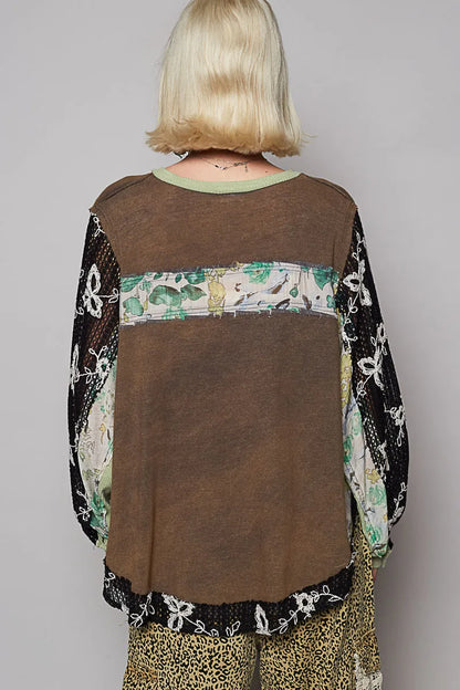 Model wearing floral patchwork blouse with crochet lace long sleeves back of blouse showing relaxed fit and floral pattern