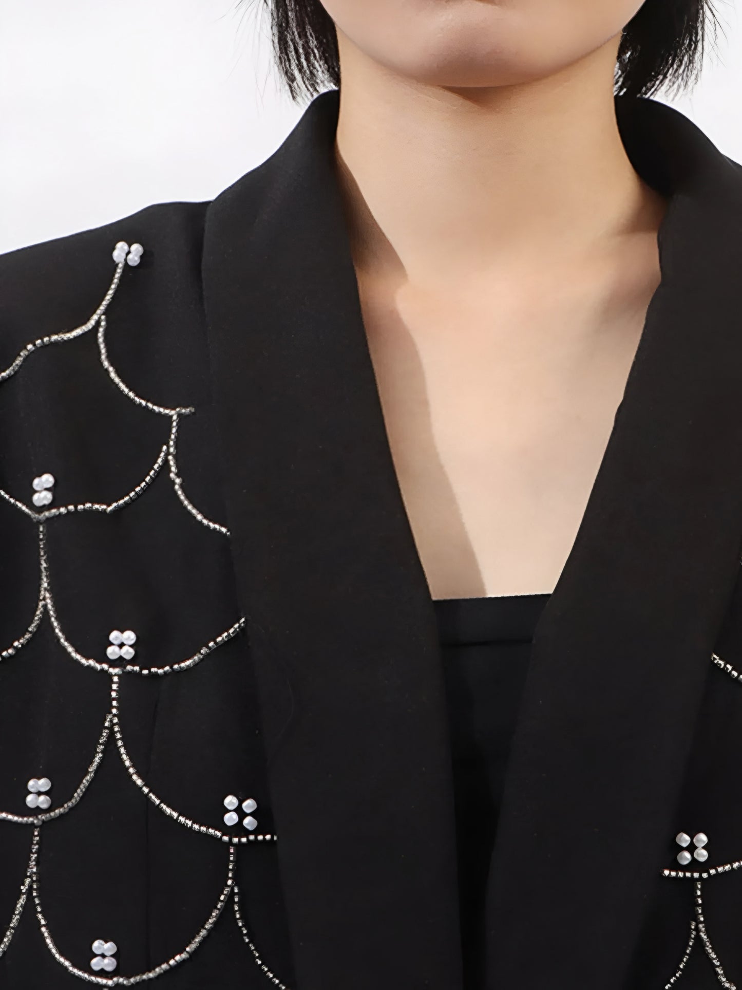 close up of neckline of black women’s tailored blazer with pearl embellishments
