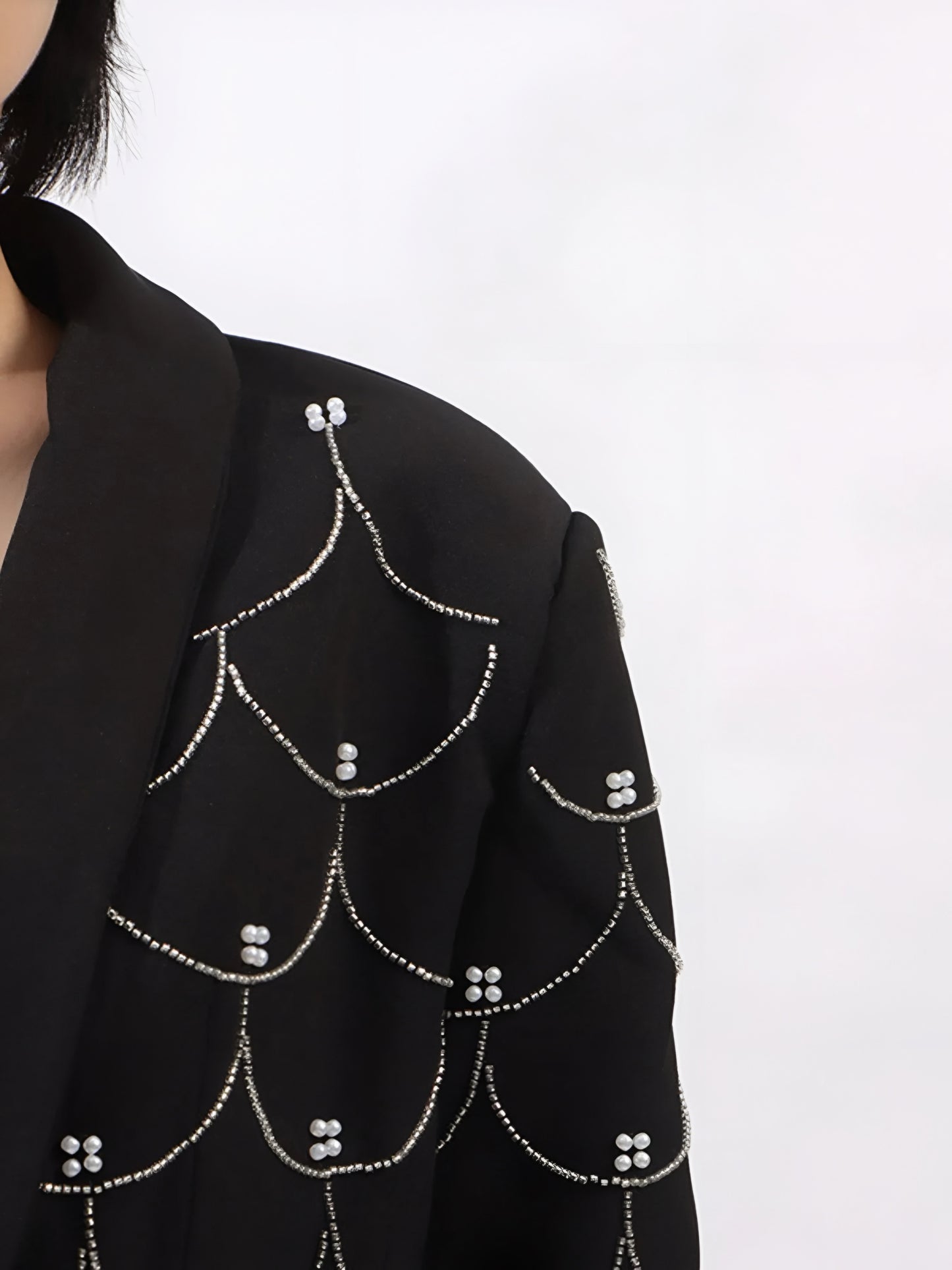 close up shoulder of women’s tailored blazer with pearl embellishments