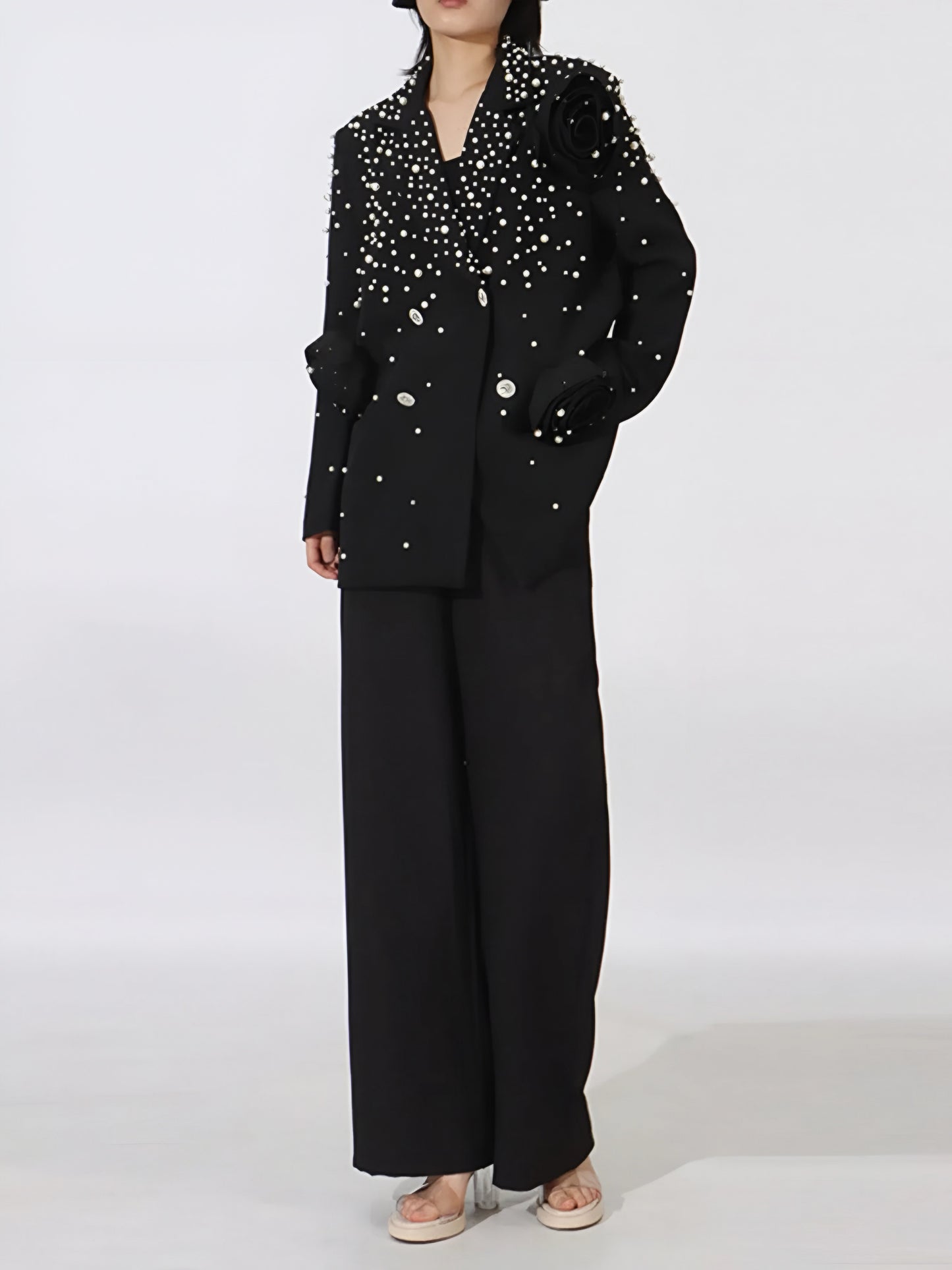 Woman wearing a elegant high fashion women’s statement blazer with crystal buttons and pearl embellishments on a white background