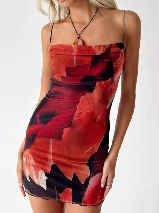 Woman wearing a red and black floral mini cami dress on a white background