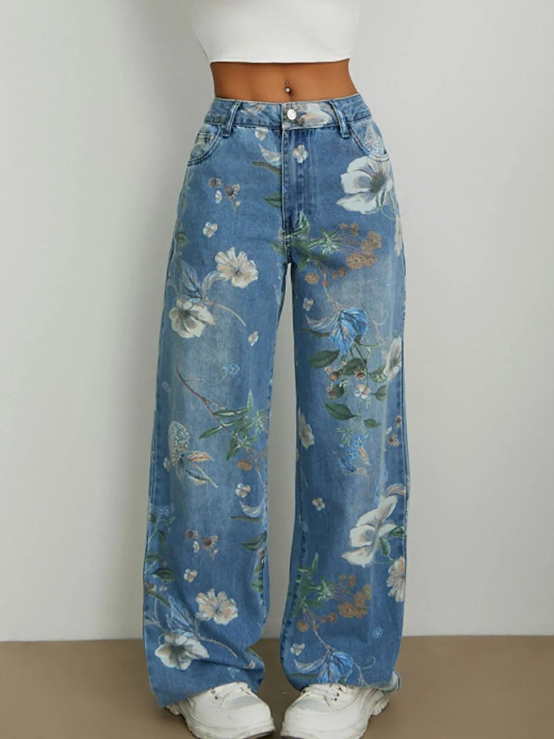 Front view of woman wearing blue floral printed relaxed wide leg loose high rise jeans on a plain background