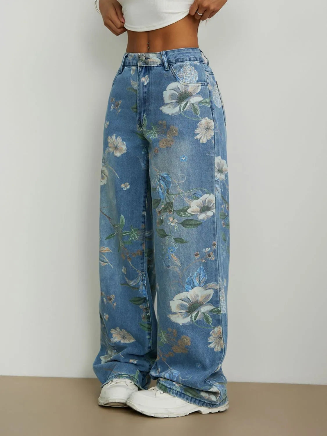 Woman wearing Blue all over printed floral  design high rise  wide leg jeans on a plain background