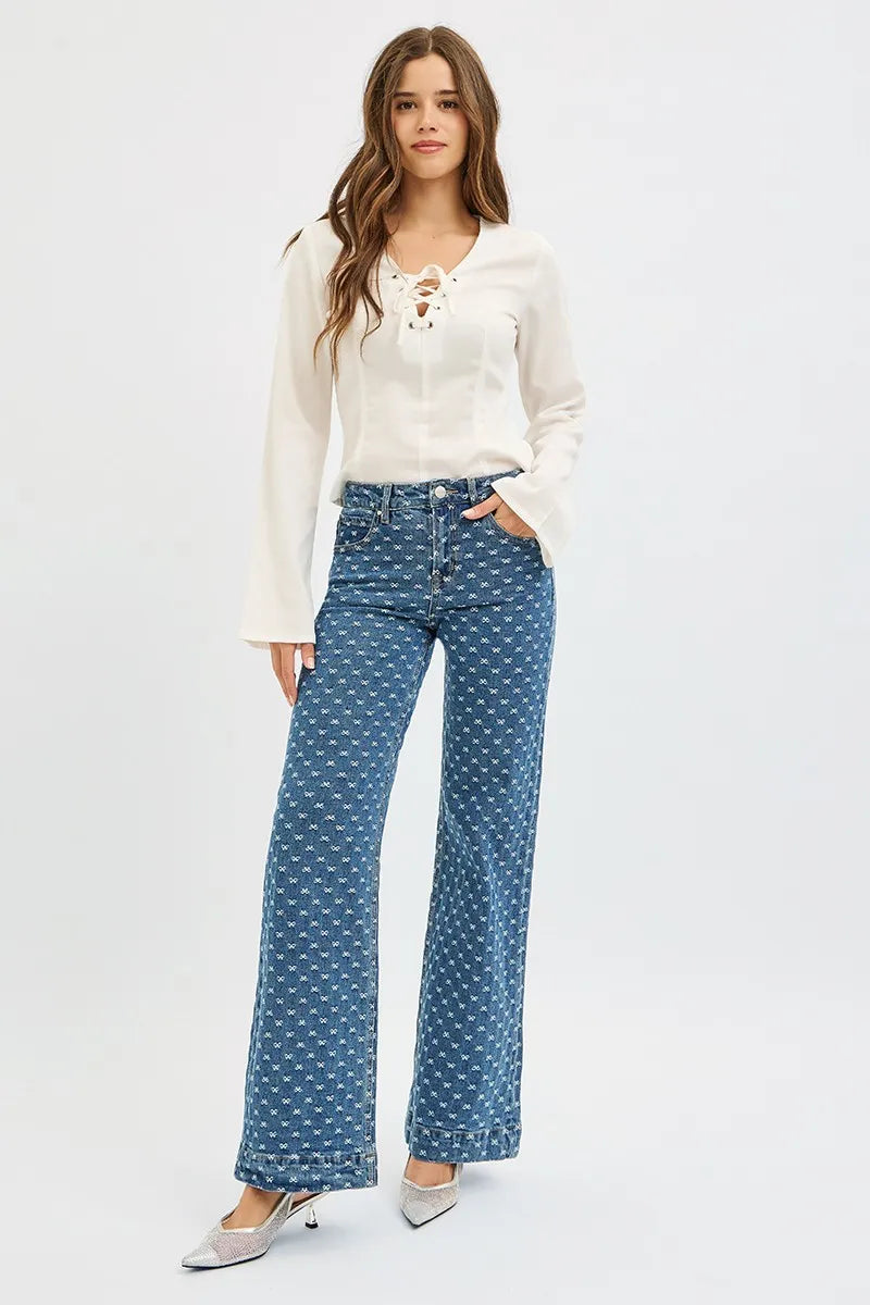 Woman wearing a white blouse and blue jeans with all over bow pattern  on a white background