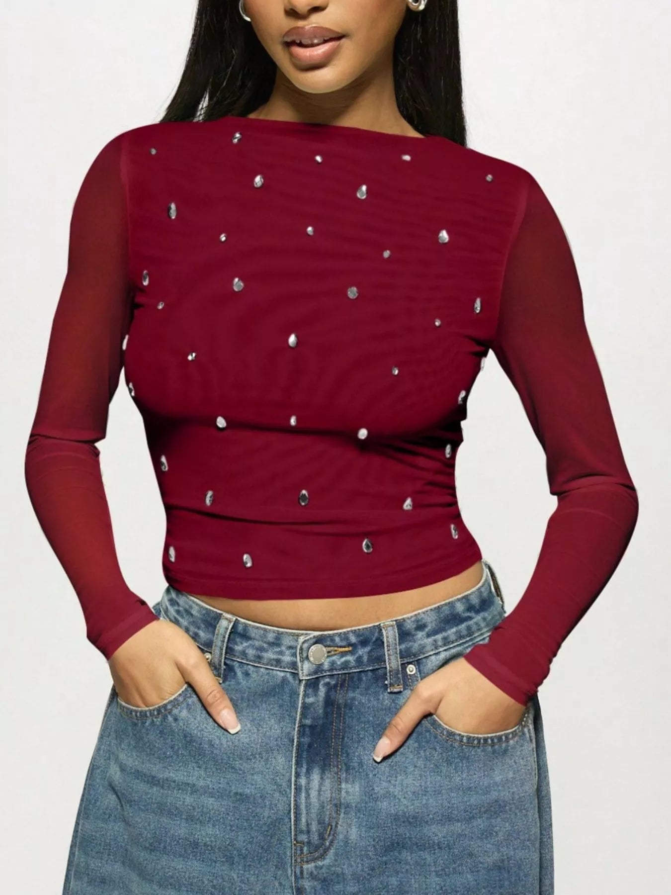 Red long-sleeve top with silver embellishments worn by a woman on a plain background