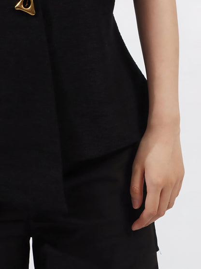 Close-up of a woman wearing a black luxury designer inspired vest coat with a gold button  and gem embellishments on a white background