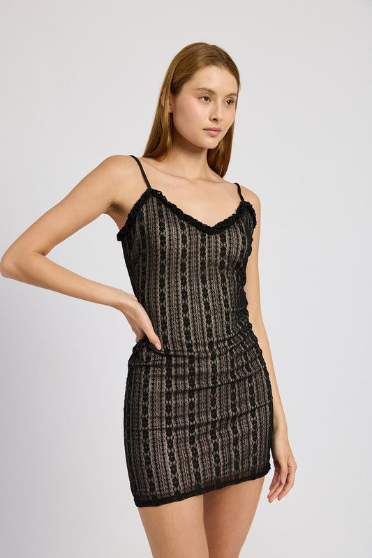 Woman posing in a chic black patterned mini dress with spaghetti adjustable straps on a white background
