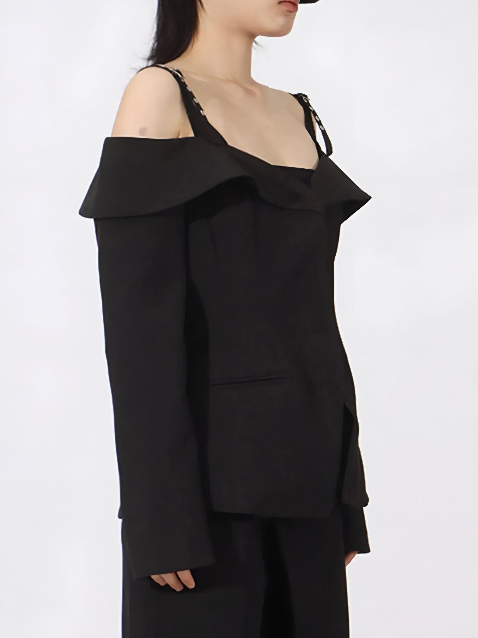 Side view of woman wearing edgy cold Shoulder Buckle Strap black Blazer on a white background