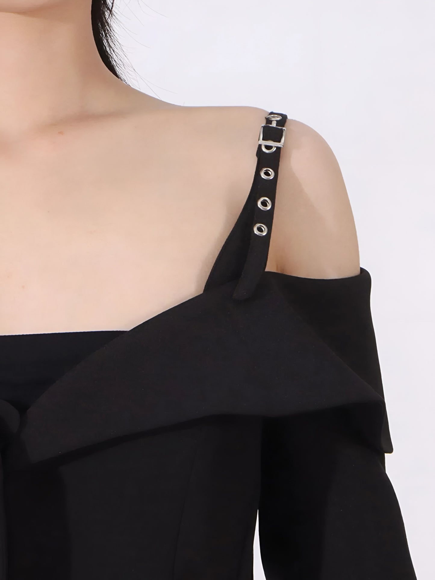 close up of buckle shoulder strap of Black off-shoulder blazer/jacket on a white background