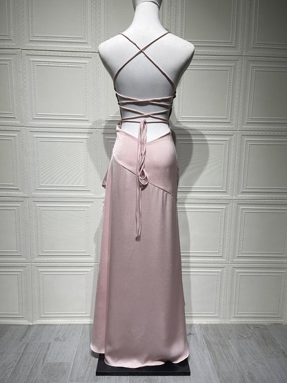 Mannequin wearing a pink dress with criss-cross backless design on a gray paneled wall background
