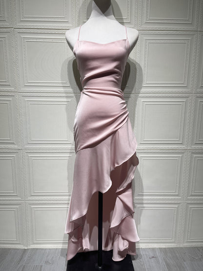 Pink evening gown on a mannequin against a white paneled wall.