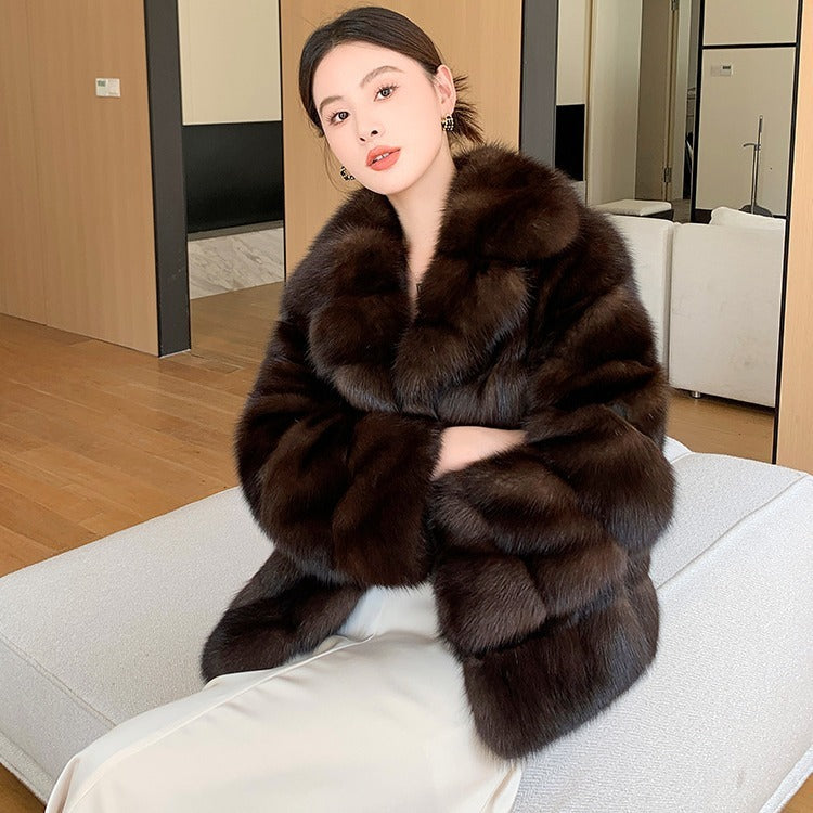 Model sitting on chair wearing a  brown luxury sable-inspired mid-length faux fur coat for women
