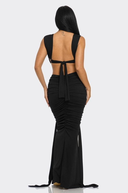 back view of woman wearing a high-fashion evening gown with daring cut-out design with metallic ring embellishments 
