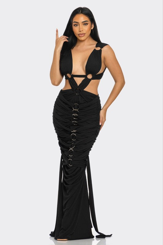 front view of woman wearing a high-fashion evening gown with daring cut-out design with metallic ring embellishments 
